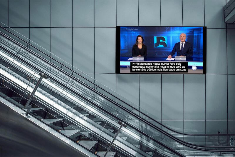 Imagem de um TV na parede de uma estação do metrô transmitindo jornal com legendas ao vivo do tipo Closed Caption