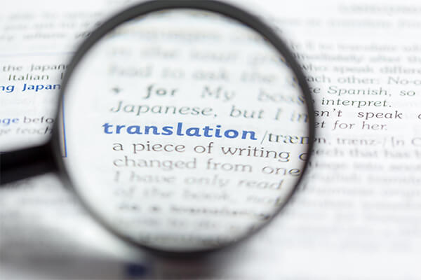 Foto de uma lupa destacando a palavra 'translation' em algum livro de escrita inglesa