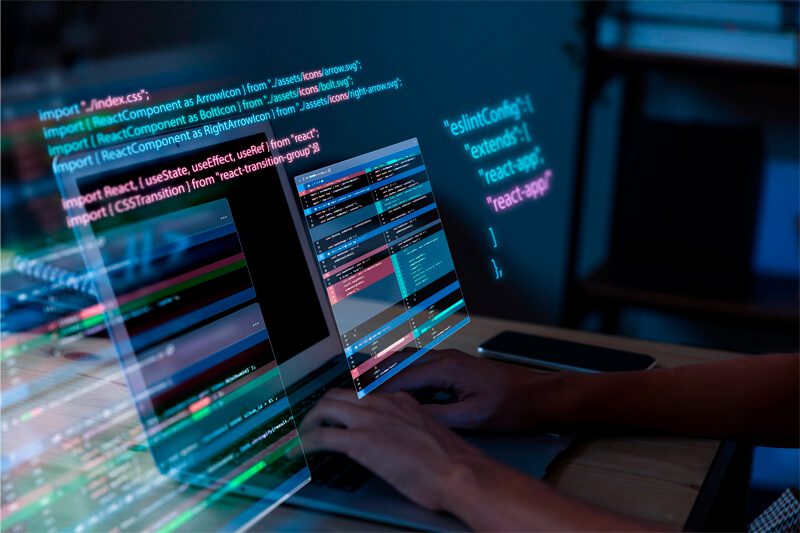 Foto de uma pessoa programando em um notebook com códigos de programação saindo da tela
